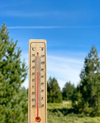 Wooden thermometer with red measuring liquid on mountain background 