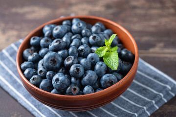 Fresh blueberries in brown ceramic bowl. Superfood rich in antioxidants summer berries