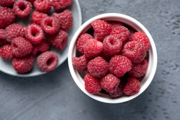 Fresh organic farm raspberries in bowl, closeup view. Juicy summer berries
