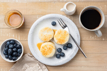Syrniki, cottage cheese fritters served with caramel sauce and blueberries and cup of black coffee