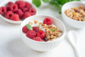 Muesli with raspberries and yogurt on grey concrete table background. Healthy diet fitness meal