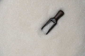White granulated sugar in wooden spoon in the background pile sugar, top view, closeup. The concept of unhealthy eating, obesity, heart disease, diabetes