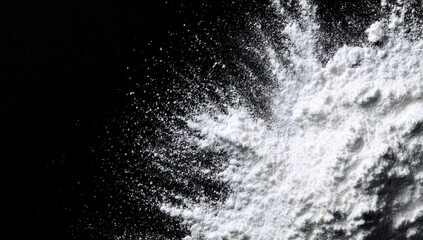 Dynamic explosion of white powder against a stark black background.