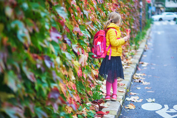 Naklejka premium Cheerful school girl enjoying her walk in autumn park in Paris, France.