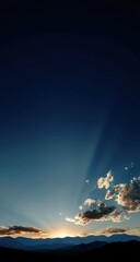 Dramatic Sunbeams Over Mountain Silhouette at Sunset.
