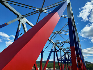Part of the automobile bridge over the river, interesting geometry of the metal trusses of the bridge, the bridge is painted in different colors