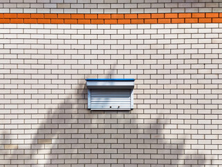 The wall is made of light brick, with a narrow strip of orange brick, in the middle of the wall there is a tiny window closed with blinds, a sketch from urban life