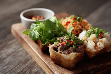 Wooden board with assorted international street food, including meat and shrimp