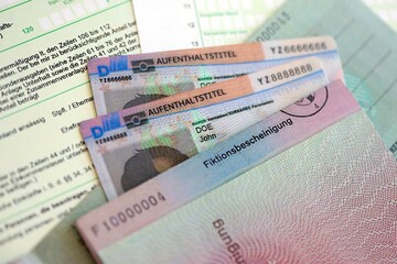 German Permanent resident card and temporary document lies on tax form. Aufenthaltstitel