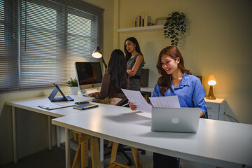Asian businesswomen collaborating, working overtime, staying late in office on project deadline, developing strategy