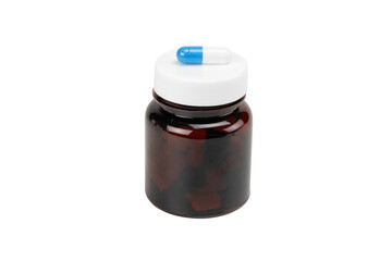 Blue and white pill capsule on the white lid of an amber medicine bottle. Concept of daily dosage, medication schedule, and treatment, isolated on white background with clipping path.