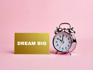 Inspirational Dream Big text and alarm clock on pink background