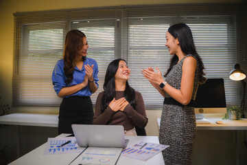 Asian businesswomen celebrating success, colleagues applauding and appreciating achievement in modern office