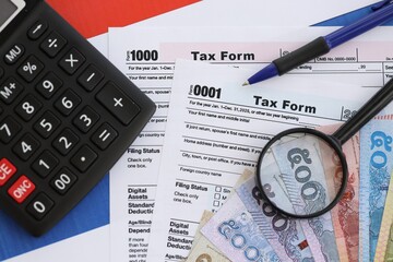 Thai baht money bills and calculator with tax form on flag. Taxation and accounting concept