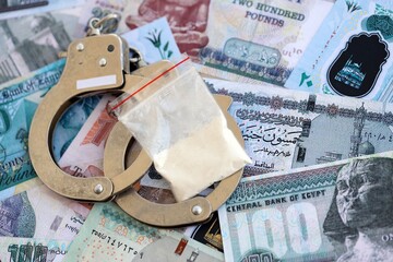 Egyptian pound currency money bills and cocaine pack with handcuffs. The concept of drug crimes