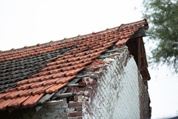 Naklejka premium A broken roof with missing tiles on an abandoned brick house in the countryside.