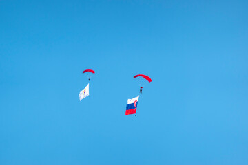 Military paratroopers flying with the flag of the Slovak Republic and the flag of the armed forces