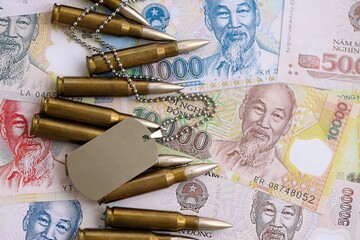 Vietnamese dong currency money bills and rifle bullets with dogtag close up. The concept of warfare...