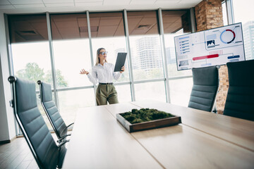 Hardworking businesswoman presenting data analysis insights in modern corporate office environment using digital tools
