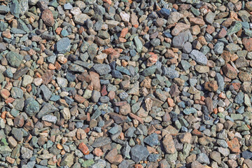 A view of a variety of river rocks and pebbles of various sizes, shapes and colors scattered on the ground
