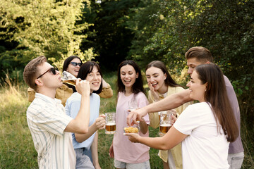 Group of happy friends having fun and drinking beer outdoors