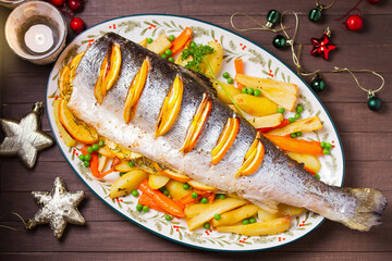 Christmas dinner. Roasted salmon with lemon, oranges and herbs. Celebration of Christmas and New Year. View from above, top studio shot