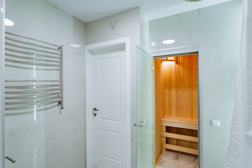 This is a sophisticated bathroom featuring a relaxing wooden sauna that provides warmth and serenity, complemented by an elegant glass door for aesthetic appeal and functionality