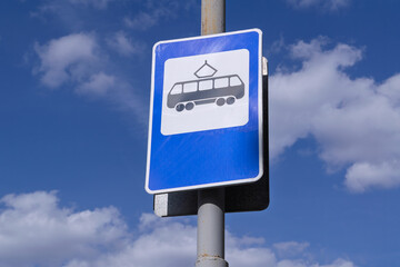 Close-up of a tram stop road sign against a blue sky.