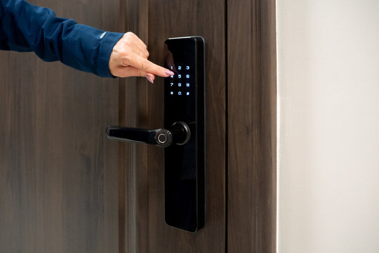 Smart door lock with keypad and hand entering code. Electronic lock system for secure access control. Hand dials the lock code. Real photo