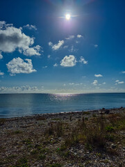 A Beautiful and Serene Coastal View Featuring a Bright Sun and Its Reflection in the Water