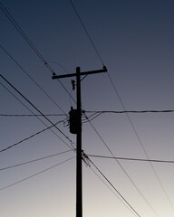 Silhouetted Transformer on power line pole 