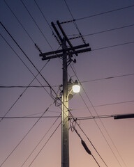 high voltage power line light pole against a purple sunset