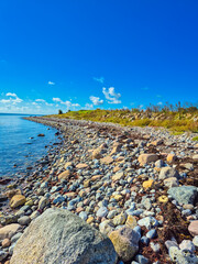 A Serene Beachfront Landscape Featuring Colorful Stones Beneath a Bright Clear Sky