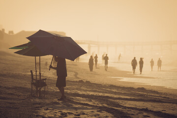 People walking and setting up umbrella on beach