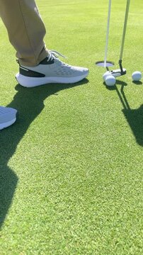 A man is standing on a golf course, holding a golf club and looking at the camera. Concept of focus and determination, as the man prepares to take a swing at the golf ball