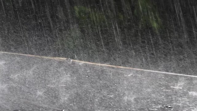Heavy rain falls on the roof of a gazebo in a garden in slow motion