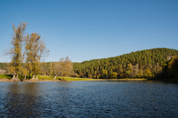 A serene lake is surrounded by colorful trees and majestic snowcapped mountains, creating an enchanting environment with breathtaking natural beauty and picturesque scenery