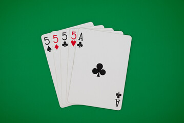 Playing cards showing four of kind poker hand on a green background, symbolizing gambling, poker, and the risks of casino games.