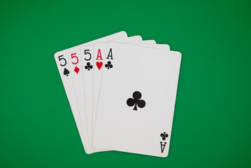 Playing cards showing full house poker hand on a green background, symbolizing gambling, poker, and the risks of casino games.