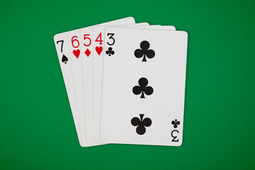 Playing cards showing straight poker hand on a green background, symbolizing gambling, poker, and the risks of casino games.