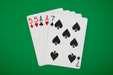 Playing cards showing two pairs poker hand on a green background, symbolizing gambling, poker, and the risks of casino games.