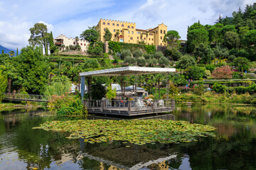 Gardens of Trauttmansdorff Castle panorama with water lily pond, flowers, trees and plants near Merano, South Tyrol, Italy