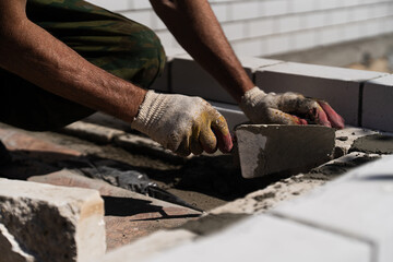Construction worker laying bricks with cement mortar at building site