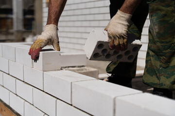 Construction worker laying bricks with cement mortar at building site