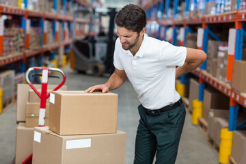 Red pallet jack lifting cardboard boxes on blue and red shelves in warehouse aisle, copy space