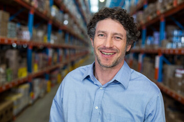 Fototapeta premium Metal shelving units are extending in warehouse aisle, holding boxes toward vanishing point