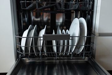 Modern dishwasher with neatly arranged clean white plates inside. Kitchen appliance for easy and efficient dishwashing. Household technology saving time and water, offering convenience and hygiene in
