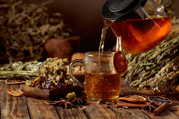 Hot herbal tea is poured into a glass mug.