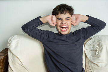 12 year old Brazilian teenager screaming and pressing his fists against his temples.