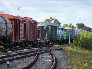 Obraz premium A freight train on a railway - A Cargo Train Traveling Through the Countryside on a Sunny Day